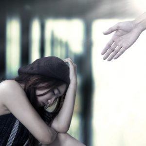Hand reaching out to depressed girl