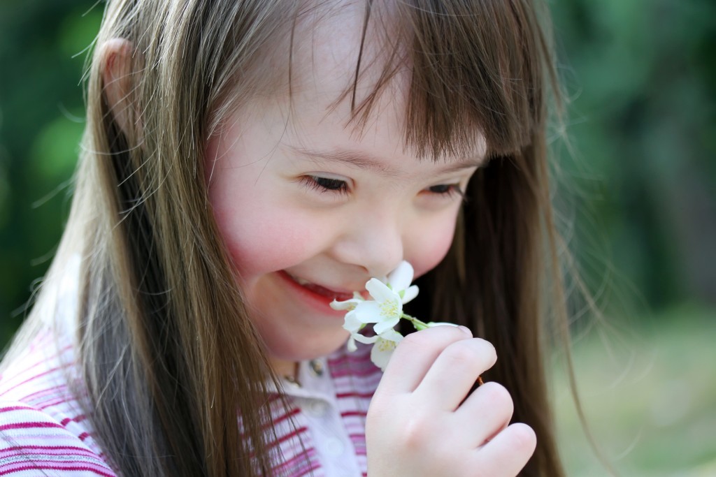 Down syndrome girl smells flower