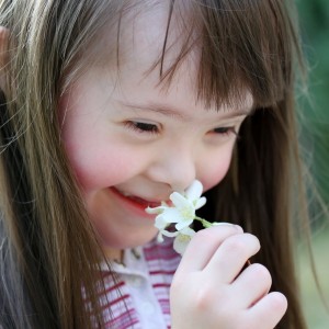Down syndrome girl smells flower