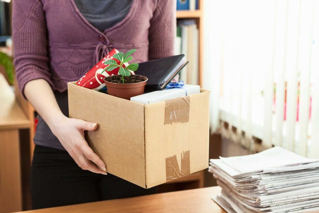Woman holds box full of desk contents